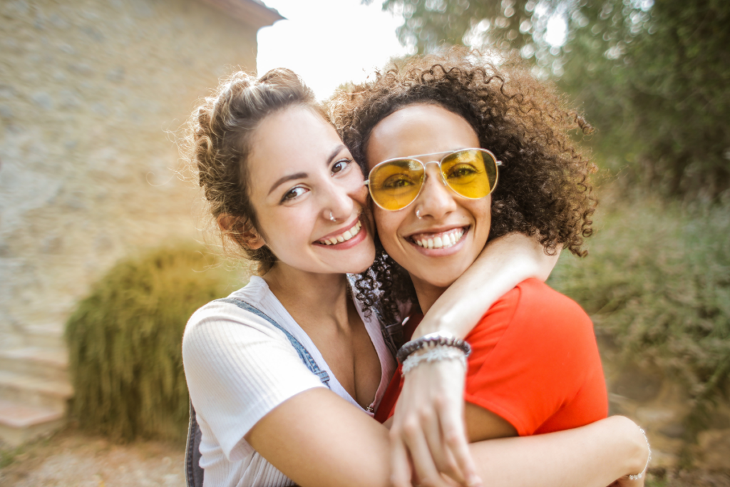Two women smiling and embracing outdoors, showing a supportive friendship during recovery from a nervous breakdown.