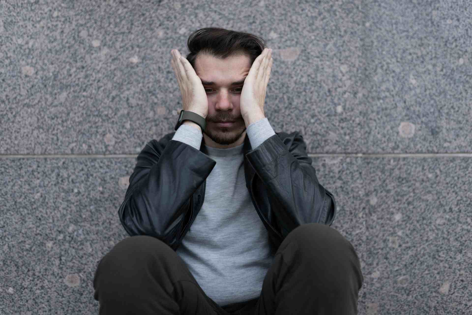 Man experiencing panic attack symptoms while sitting against a wall