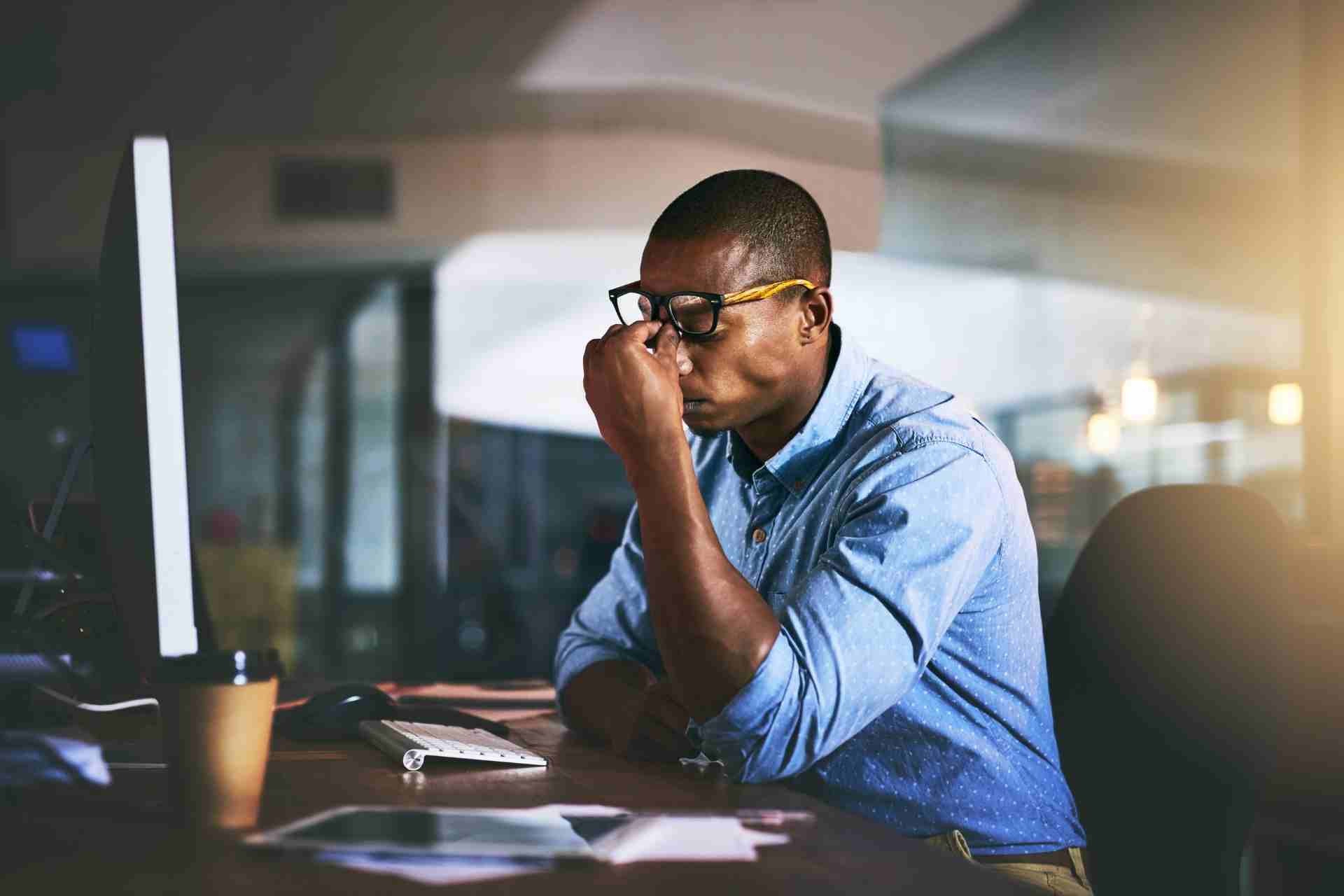 Professional experiencing anxiety and emotional stress at work while sitting at a desk in front of a computer.