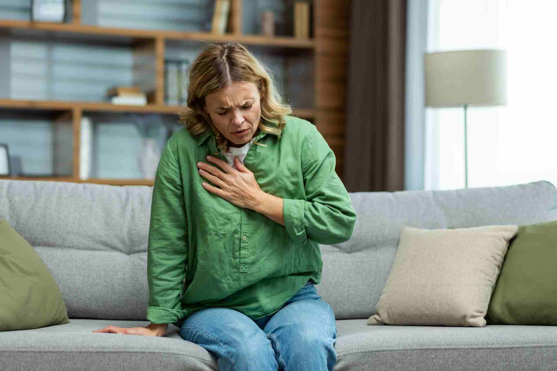 Woman experiencing panic attack symptoms including chest discomfort at home.
