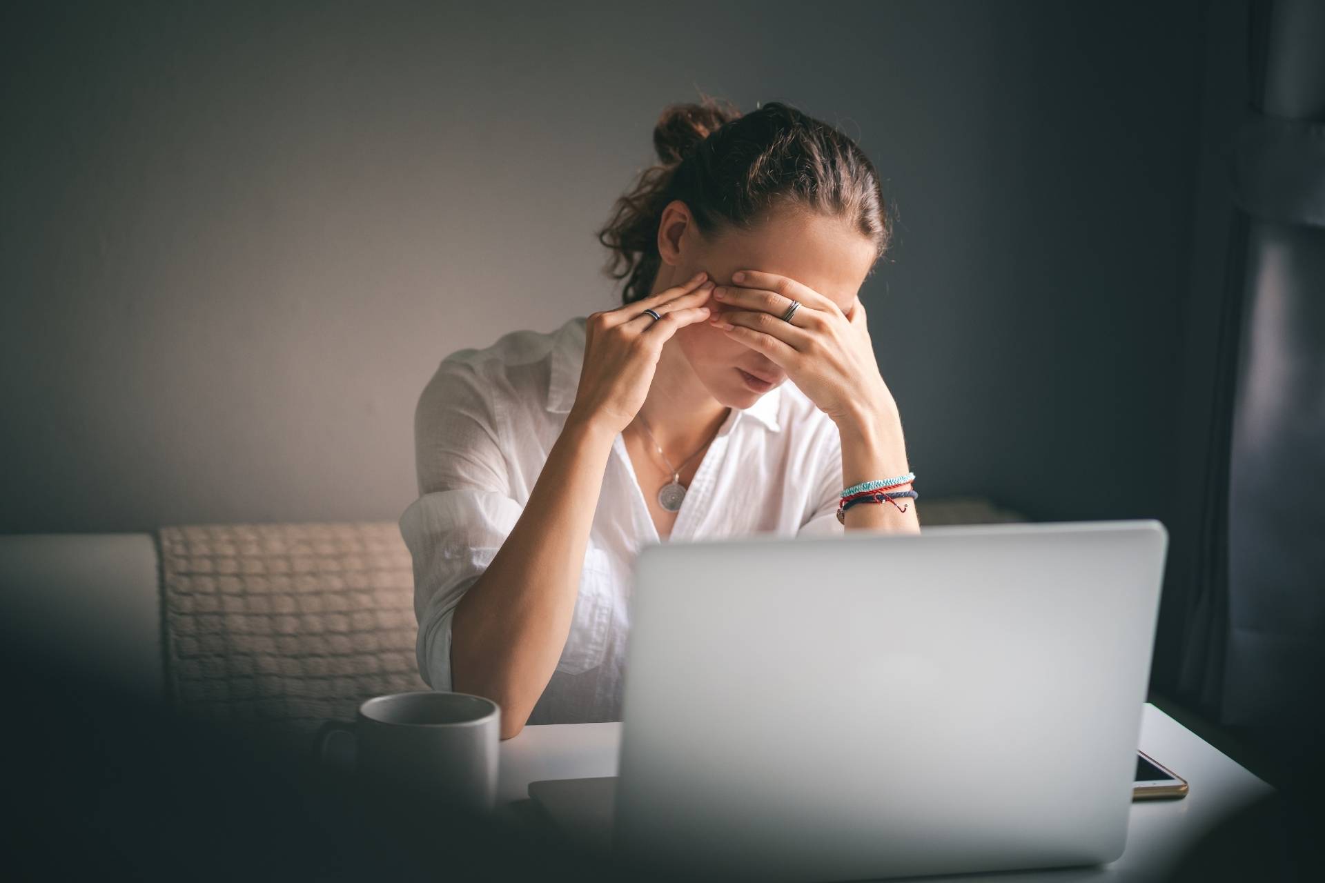 Woman experiencing burnout and mental exhaustion while working on a laptop at home.